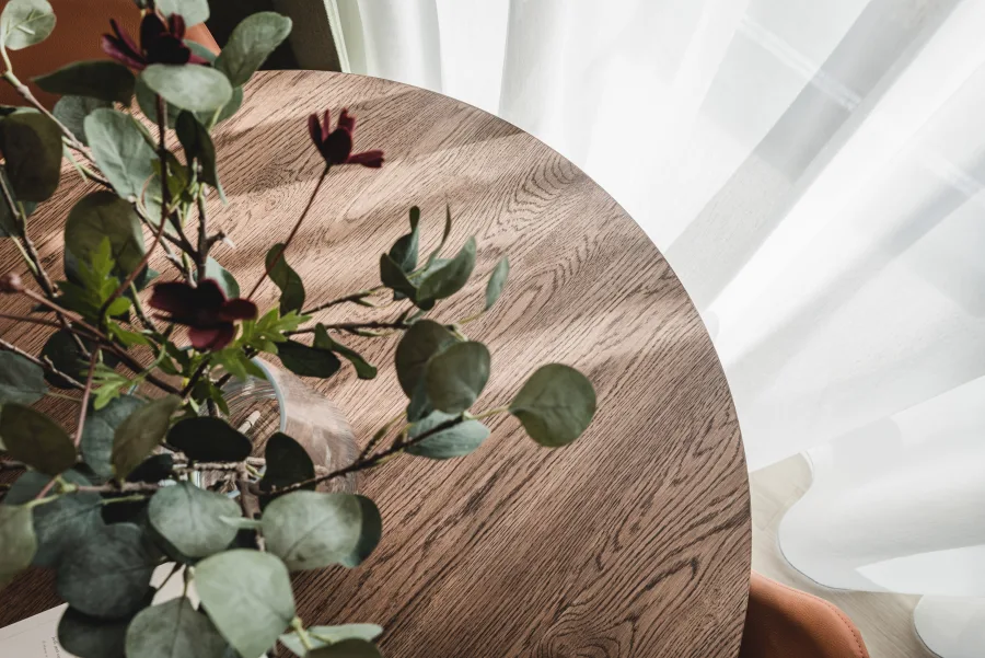 Round wooden headboard detail with eucalyptus plant arrangement