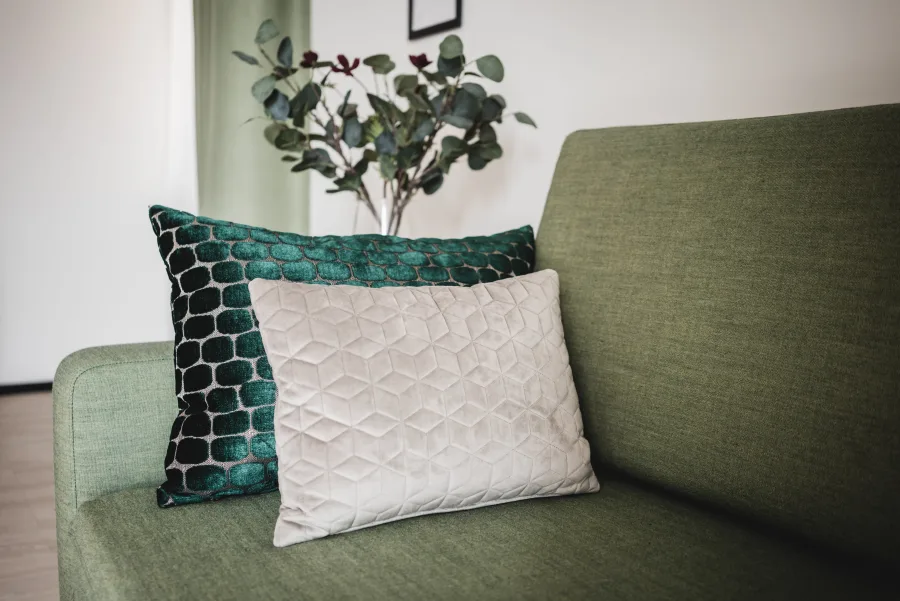 Green sofa with decorative cushions and eucalyptus arrangement