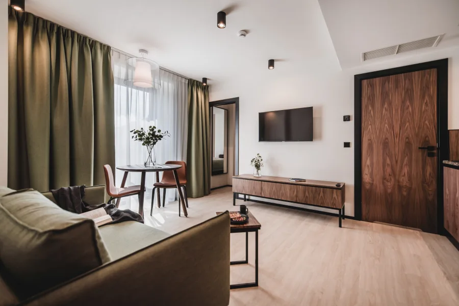 Hotel room entry view showing bed and kitchenette behind glass partition