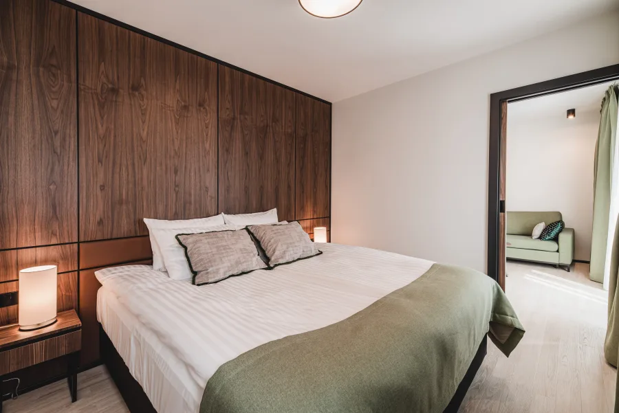 Bedroom corner with green armchair, walnut headboard wall