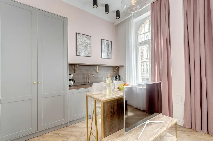 Grey kitchen with pink walls, marble bar counter, and arched window in the Sowa Gdansk apart-hotel