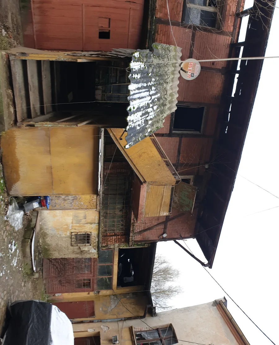 Before: rear courtyard view showing the three separate pitched-roof masses behind the street facade in advanced state of structural deterioration