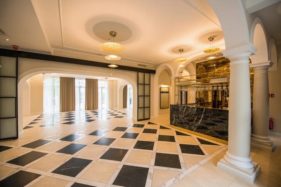 Lobby with columns, glass partition, pendants, and marble bar visible through archway