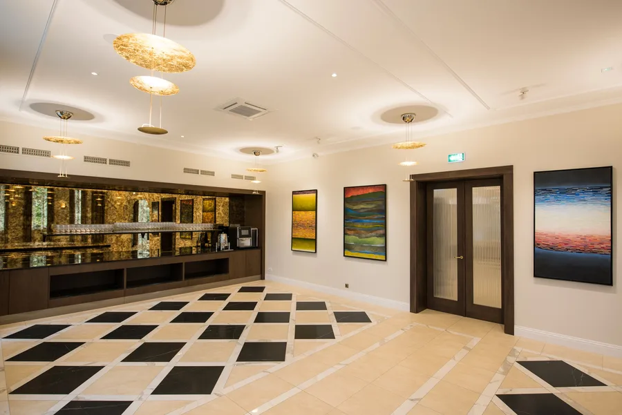 Bar area with gold mirrored wall, landscape paintings, and gold pendant chandeliers