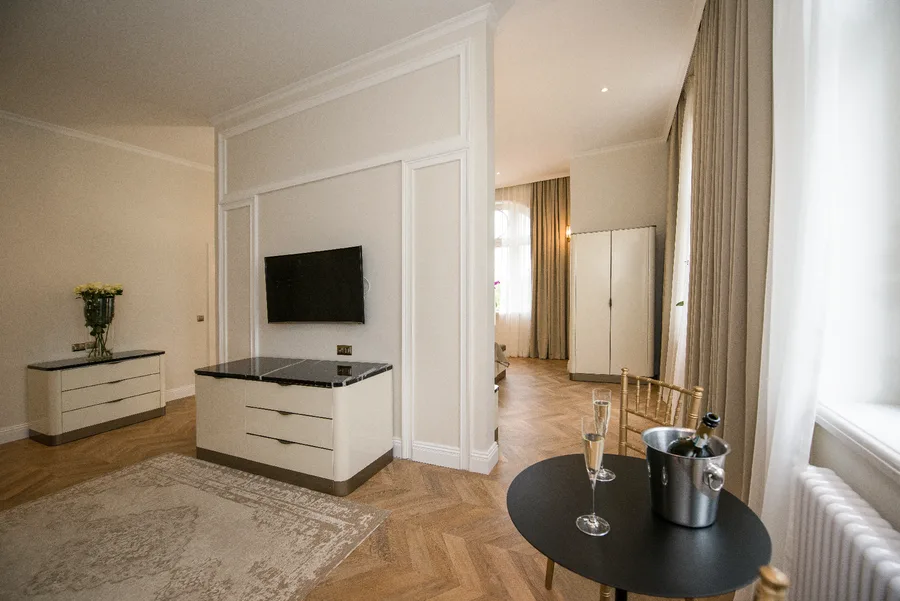 Hotel room living area with TV unit, drawers, and warm pendant lighting