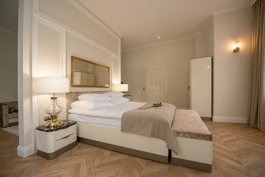 Hotel room bedroom with gold-framed mirror and white bed linen