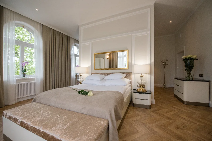 Hotel room bedroom wider view with arched window, roses, and heritage ceiling height