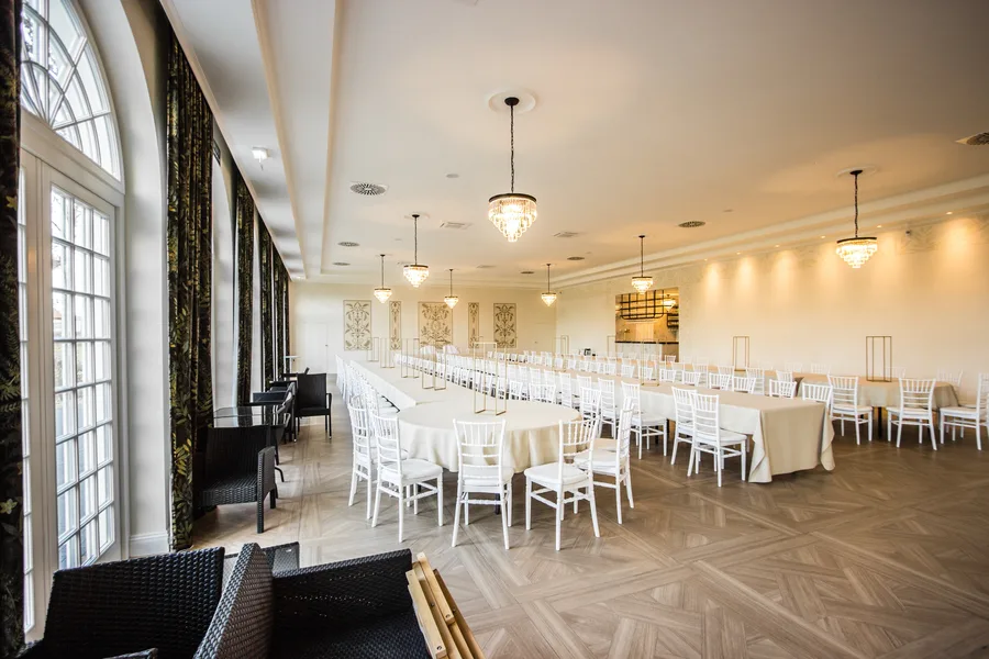 Orangerie ballroom wide view with long banquet tables, arched windows, and chandeliers — best overview