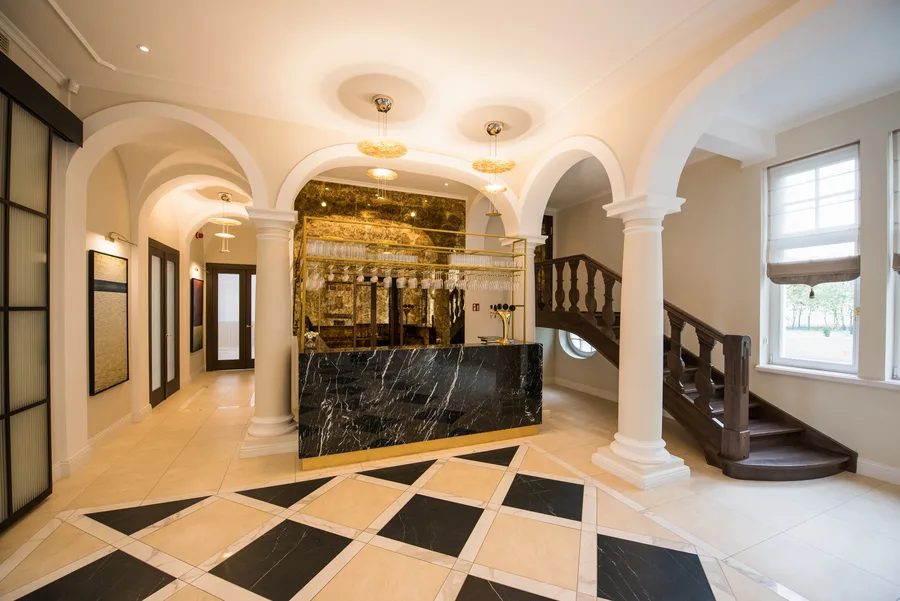 Palace lobby from staircase side showing marble desk, arched columns, and diamond checkered floor stretching through the ground floor circulation