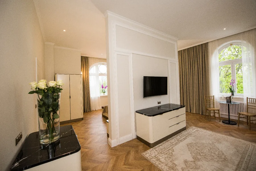 Hotel suite living room with herringbone floor, TV unit, and warm pendant lighting
