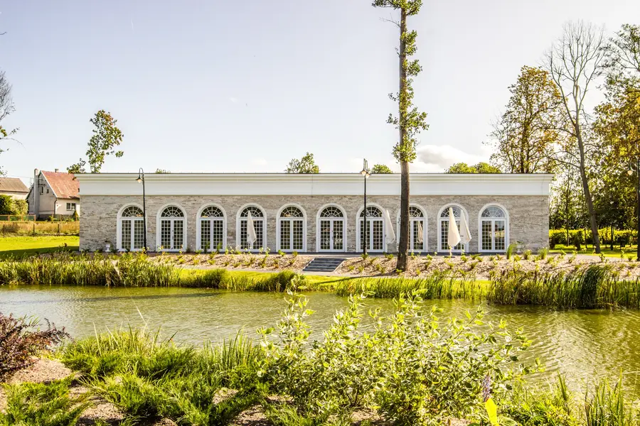 Orangerie viewed across reed-fringed pond with building reflected in water