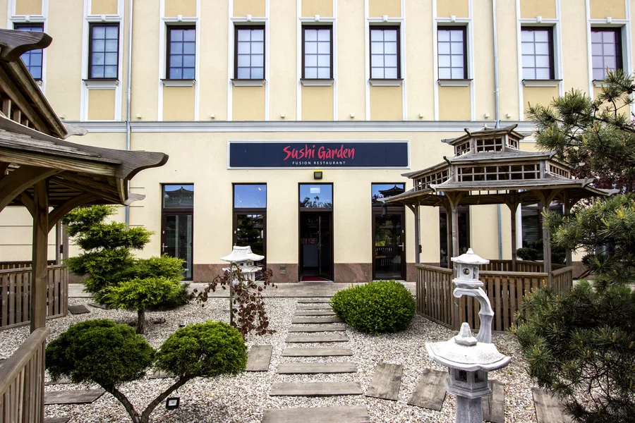 Exterior: facade with Sushi Garden signage, Japanese garden path, stone lanterns, pagodas, evergreen trees