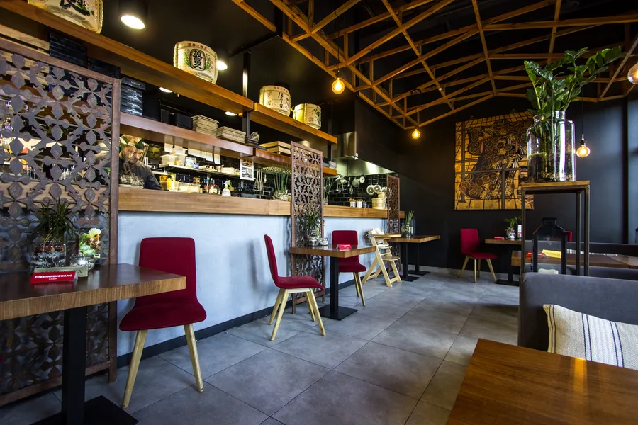 Interior: wide bar view — counter and sake barrel shelf, Klimt panel, dining room depth, lattice ceiling