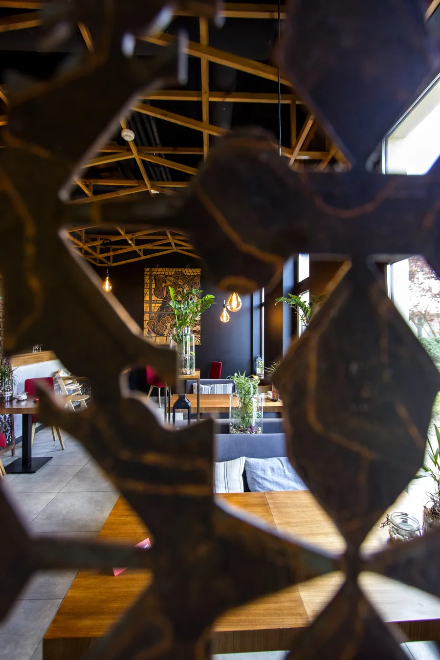 Interior: framing through metal screen — pattern in sharp foreground, dining room through cutout